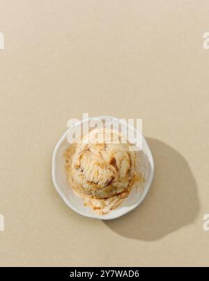 Schüssel Karamell-Eis isoliert auf beigem Hintergrund, Draufsicht Stockfoto