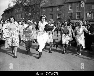 Das jährliche Pancake-Rennen in Olney, Bucks. - Faschingsdienstag Frau Isabel Dix 22, gewann das Pfannkuchenrennen der Housfrauen am Faschingsdienstag - Kunde über 500 Jahre alt - in Olney, Bucks . Sie legte den 415-Meter-Kurs von der Dorfpumpe bis zum Kirchentor in 1 Minute 12 1/10 Sekunden zurück - schneller als im letzten Jahr um einen Bruchteil einer Sekunde - und drehte ihren Pfannkuchen dreimal in der Pfanne um , während sie lief , gemäß den Regeln . Zum zweiten Mal in Folge fand ein Rennen unter ähnlichen Bedingungen gleichzeitig in Liberal , Kansas , USA statt . Die Zeiten werden per Telefon und t verglichen Stockfoto