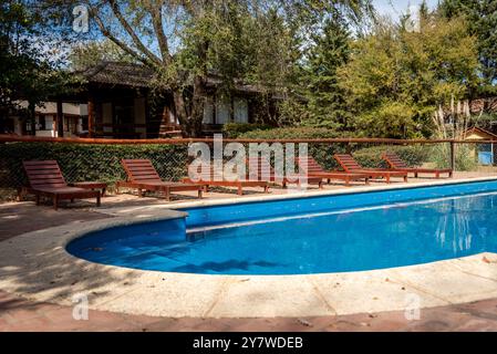 Entspannende Szene mit hölzernen Liegestühlen um einen Swimmingpool an einem hellen sonnigen Tag Stockfoto