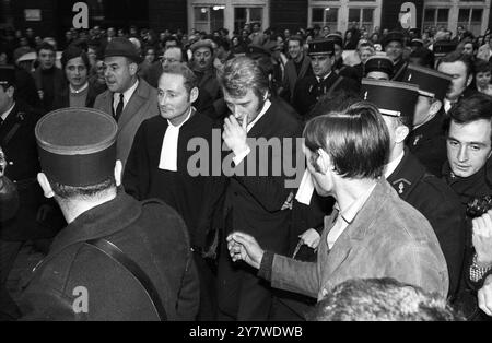 Eine riesige Menge von Fans und Nachrichtensprechern umzingelt den französischen Popsänger Johnny Hallyday (Mitte), als er am 24. November 1967 im Pariser Gerichtsgebäude ankam, um wegen Verkehrsdelikten zu erscheinen. Stockfoto