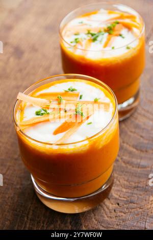 Karotten- und Orangensuppe mit Soja-Joghurt im Glas, garniert mit Schnittlauch und Karottenstreifen Stockfoto