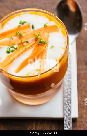 Karotten- und Orangensuppe mit Soja-Joghurt im Glas, garniert mit Schnittlauch und Karottenstreifen Stockfoto