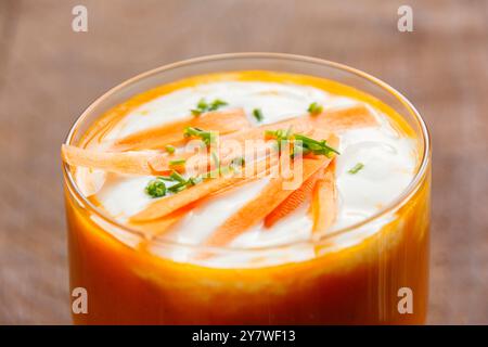 Karotten- und Orangensuppe mit Soja-Joghurt im Glas, garniert mit Schnittlauch und Karottenstreifen Stockfoto