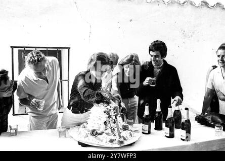 Glückliche 27. Geburtstagsfeier für die deutsche Schauspielerin Romy Schneider. Sie schneidet den Kuchen, gekrönt mit einem kunstvollen Zifferblatt, das von (von links) Peter Finch , dem australischen Schauspieler , Jules Dassin (teilweise verborgen), dem französischen Filmregisseur , der griechischen Schauspielerin Melina Mercouri und Julian Mateos , einem spanischen Schauspieler, beobachtet wird, die alle mit Romy in "10,30 pm Summer " filmen. 28. Februar 1965 Romy Schneider 1938–1982 war eine deutsche Schauspielerin, die ebenfalls die französische Staatsbürgerschaft innehatte. Stockfoto