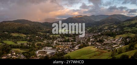 Die Panoramalandschaft der Stadt Ambleside im Lake District mit Loughrigg fiel zurück und Sturmwolken mit Regen bei Sonnenaufgang Stockfoto
