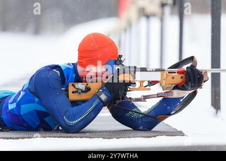 Sportlerschießen in Bauchlage auf der Strecke bei einem Biathlonwettbewerb. Stockfoto
