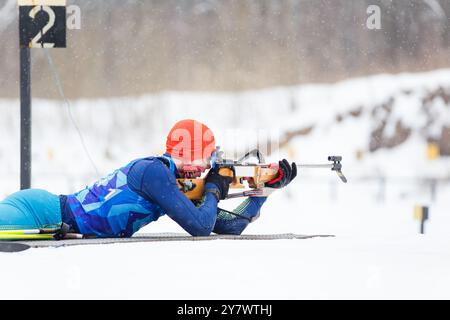 Sportlerschießen in Bauchlage auf der Strecke bei einem Biathlonwettbewerb. Stockfoto