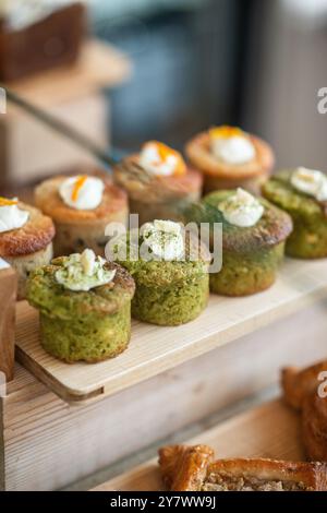 Dekorierte Muffins werden auf der Theke eines Coffee Shops arrangiert. Seitenansicht Stockfoto