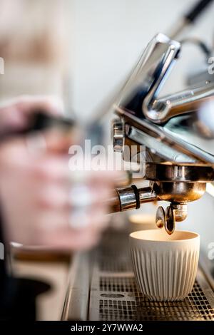 Moderne Kaffeemaschine in einem Café im minimalistischen Stil. Die Hand eines Mannes wird gezeigt, wie er Kaffee zubereitet. Stockfoto