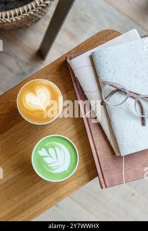 Tasse Matcha Latte und Tasse Cappuccino auf hölzernem Coffee Shop Tisch. Draufsicht. Stockfoto