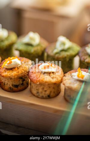 Dekorierte Muffins werden auf der Theke eines Coffee Shops arrangiert. Seitenansicht Stockfoto