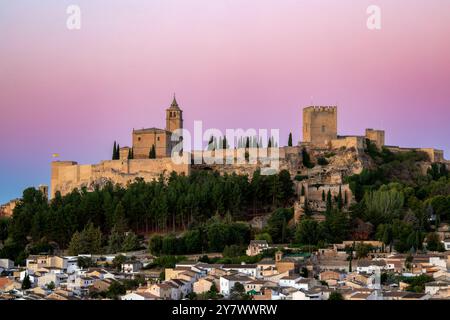 La Mota Festung in Alcalá la Real, Jaén, Andalusien, Spanien, mit rosafarbenem Sonnenaufgangslicht und der Stadt darunter Stockfoto