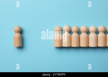 Einsamkeitskonzept. Menschliche Figur, die von anderen entfernt ist, auf hellblauem Hintergrund, Ansicht von oben Stockfoto