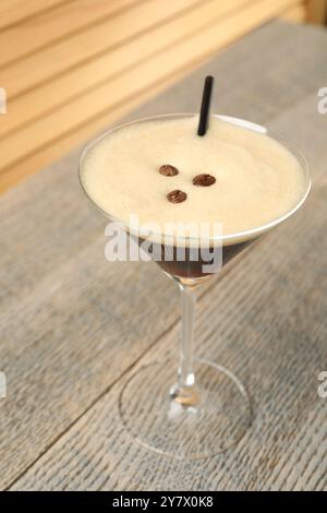 Köstlicher Espresso-Martini mit Kaffeebohnen im Glas auf Holztisch Stockfoto