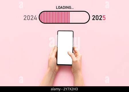 Hände halten Mobiltelefon und Statusleiste mit den Jahren 2024 und 2025 auf rosafarbenem Hintergrund Stockfoto