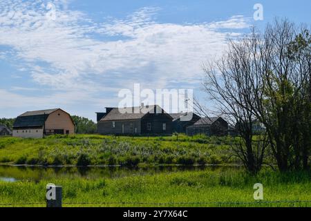 Holzhütten umgeben von Natur und einem See im Ukrainischen Heritage Village in Kanada, an einem sonnigen Tag Stockfoto