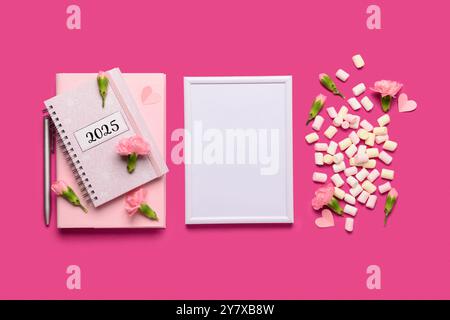 Bilderrahmen mit Notizbuch und Blumen auf rosa Hintergrund Stockfoto