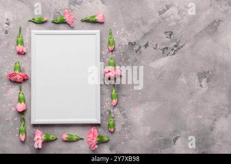 Leerer weißer Rahmen mit rosafarbenen Blumen auf grauem Marmorhintergrund Stockfoto