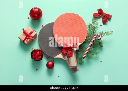 Komposition mit Tischtennisschlägern, Weihnachtsgeschenk und Dekoration auf farbigem Hintergrund Stockfoto