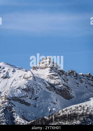 Ein atemberaubender Blick auf die schneebedeckten Gipfel von Serre Chevalier in der Nähe von Briancon, Frankreich. Die zerklüfteten Berge erheben sich unter einem klaren blauen Himmel, mit Streulicht Stockfoto