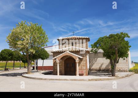 Kleine Steinkirche mit Holztür, flankiert von Bäumen unter einem klaren blauen Himmel, Ermita de San Anton, Eremitage von San Anton, Villahermosa, La Mancha, C. Stockfoto