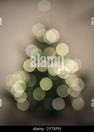 Ein weiches, unscharfes Bild mit Bokeh-Lichtern in Form eines Weihnachtsbaums. Die runden Lichter in warmen Tönen schaffen ein festliches und traumhaftes Ambiente Stockfoto