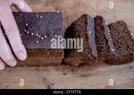 Roggenbrot in Scheiben geschnitten Foto. Der Mann schneidet Vollkorn-Roggenbrot auf einem hölzernen Schneidebrett. Stockfoto