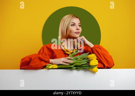 Elegante junge Frau, die einen Strang Tulpen auf den Kopierraum vor gelbem Hintergrund lehnt Stockfoto