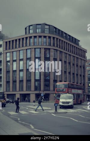 11. september 2024 - London großbritannien : belebte Straße mit Fußgängerüberquerung und modernem Wohnblock mit verblasster Farbbearbeitung Stockfoto