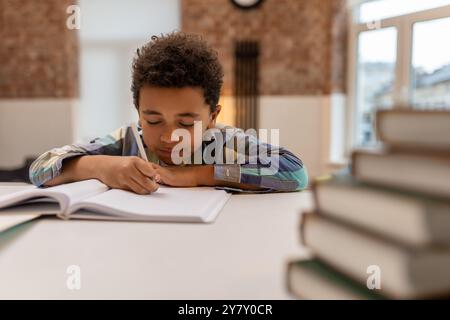 Dunkelhäutiger, süßer Junge, der Unterricht macht und sich beteiligt sieht Stockfoto