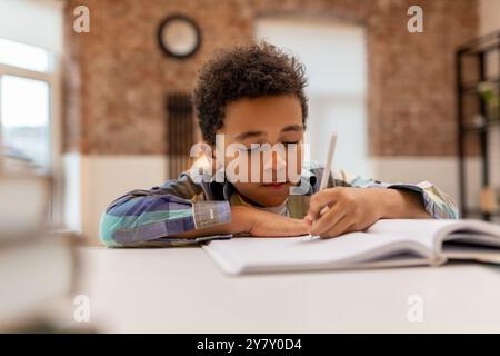 Dunkelhäutiger, süßer Junge, der Unterricht macht und sich beteiligt sieht Stockfoto