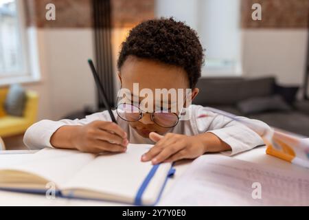 Dunkelhäutiger, süßer Junge, der Unterricht macht und sich beteiligt sieht Stockfoto