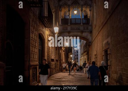 Die Leute laufen entlang der Bisbe Straße (carrer del Bisbe) und der Brücke an der Gloaming in Barcelonas gotischem Viertel, einem der wichtigsten Touristenattraktionen der Th Stockfoto