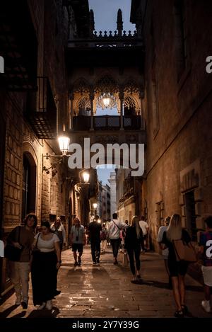 Die Leute laufen entlang der Bisbe Straße (carrer del Bisbe) und der Brücke an der Gloaming in Barcelonas gotischem Viertel, einem der wichtigsten Touristenattraktionen der Th Stockfoto