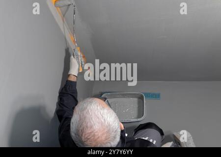 Ein Bauarbeiter, der Wasserabdichtungsfarbe auf die Wand und den Boden des Badezimmers aufträgt. Imprägnierung im Badezimmer. Stockfoto