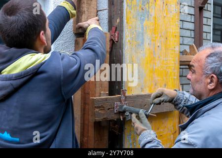 Der Arbeiter installiert und montiert Säulenschalungen für die Betonfüllung auf der Baustelle. Holzsäulenschalung mit Bolzen am Mauerwerk befestigt. Konz Stockfoto