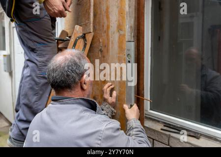 Der Arbeiter installiert und montiert Säulenschalungen für die Betonfüllung auf der Baustelle. Holzsäulenschalung mit Bolzen am Mauerwerk befestigt. Konz Stockfoto