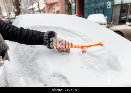 Fahrt im Winter. Nahaufnahme einer Hand, die die Windschutzscheibe eines Fahrzeugs von Eis und Schnee reinigt. Transport, Winter, Wetter, Menschen und Fahrzeug Stockfoto