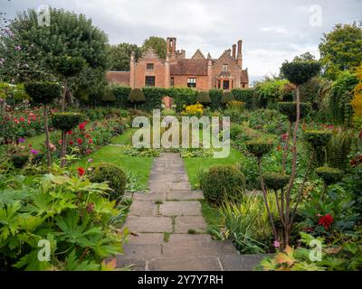 Chenies Manor Sunken Garden im September gegenüber dem Haus. Gepflasterte und grasbewachsene Wege führen das Auge durch mit voll gepackten Dahliensorten an den Grenzen. Stockfoto