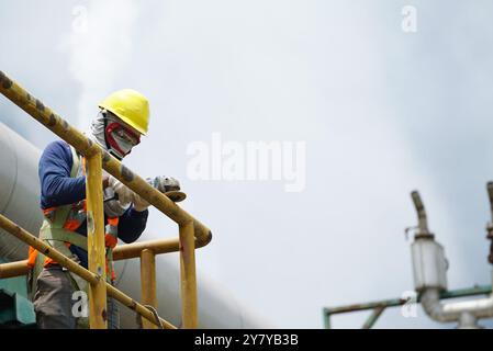 Männlicher Schweißer, der Schutzkleidung trägt, Befestigung, Schweißen und Schleifen von Industriebauöl und -Gas oder Wasserleitungen im Freien auf en Stockfoto