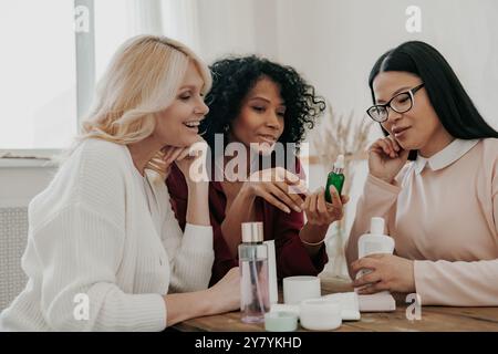 Drei reife Frauen untersuchen Schönheitsbehandlungen, während sie zusammen am Schreibtisch sitzen Stockfoto