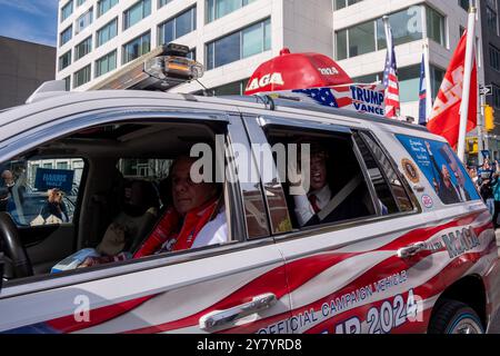 New York, Usa. Oktober 2024. Ein Mann fährt in einem "offiziellen Kampagnenmobil" vorbei, komplett mit Trump-Schaufensterpuppe auf dem Rücksitz. Eine Frau, die durch das Fenster gesehen wurde und ein Harris/Walz-Schild hält. Anhänger von Harris und Trump versammelten sich vor den CBS-Studios Stunden vor Beginn der Debatte zwischen Tim Walz und JD Vance. Quelle: SOPA Images Limited/Alamy Live News Stockfoto