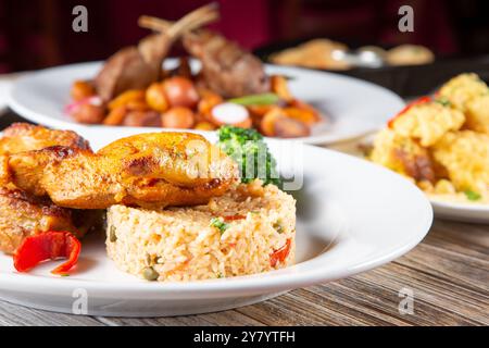 Blick auf mehrere Hauptgerichte auf einem Tisch mit gebratenem Huhn und Reis. Stockfoto