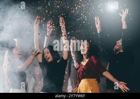 Gruppe glücklicher junger Freunde tanzen und werfen Konfetti, während sie im Nachtclub feiern Stockfoto
