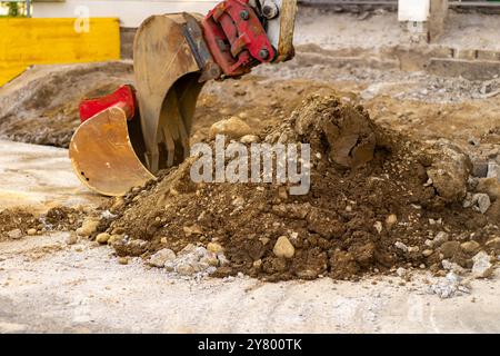 Baggerlöffel sammelt Erde und alten Asphalt auf einer Baustelle. Stockfoto