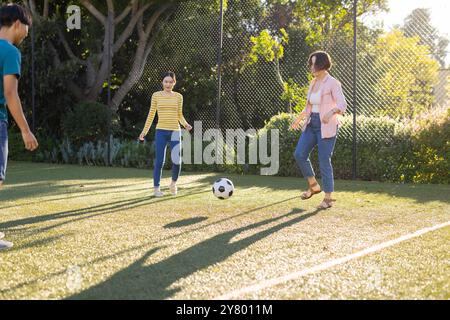 Fußball auf dem Spielfeld, asiatische Familie, die gemeinsam Outdoor-Aktivitäten im Park macht Stockfoto