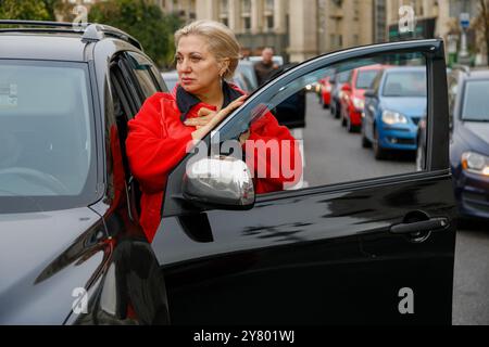 KIEW, UKRAINE - 01. SEPTEMBER 2024 - Eine Fahrerin steht während einer landesweiten Schweigeminute am Tag der Verteidiger der Ukraine an ihrem Auto, auf dem Maidan-Nezalezhnosti-Platz in Kiew, Hauptstadt der Ukraine Stockfoto