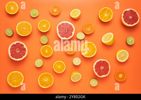 Frisches, fruchtiges und saftiges Fruchtkonzept. Ansicht von oben. Frisch geschnittene Scheiben von Zitrusfrüchten auf orangefarbenem Hintergrund. Stockfoto