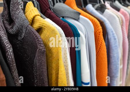 Damenbekleidung – Herbst Winter Kollektion. Modische Strickkleidung, hängend an Regalen zur Ausstellung. Lässige Damen-Pullover, Angebotssaison. Mehrfarbiges W Stockfoto