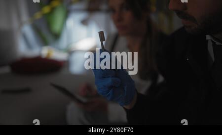 Ein Mann und eine Frau in Handschuhen analysieren Beweise an einem drinnen Tatort. Stockfoto